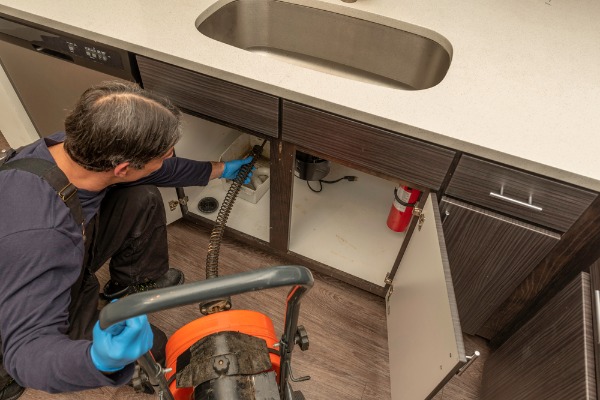plumber clearing kitchen sink drain
